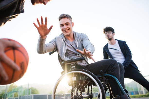 Participant in a wheelchair playing basketball with friends