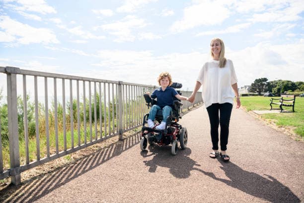 Participant operating an electric wheelchair with a family member
